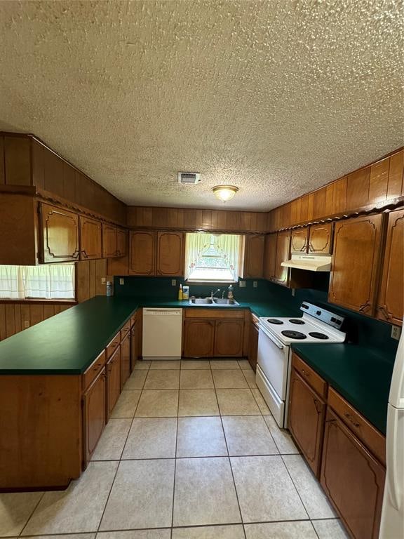 kitchen featuring a textured ceiling, sink, light tile patterned floors, and white appliances