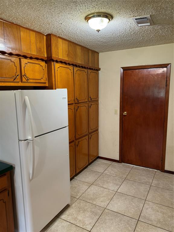 kitchen featuring white refrigerator, light tile patterned floors, and a textured ceiling