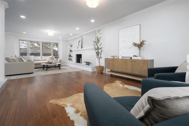 living room with dark hardwood / wood-style floors, built in features, ornamental molding, and a fireplace