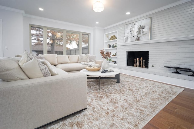 living room featuring hardwood / wood-style floors, a brick fireplace, and crown molding