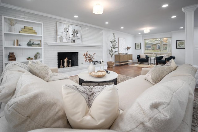 living room featuring hardwood / wood-style flooring, crown molding, and a brick fireplace