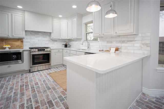 kitchen featuring sink, stainless steel appliances, tasteful backsplash, kitchen peninsula, and white cabinets