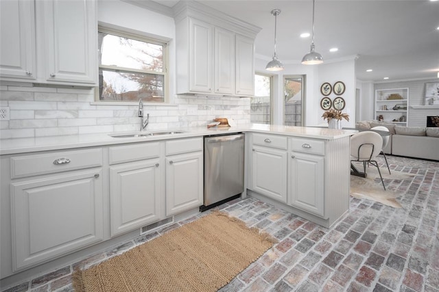 kitchen featuring backsplash, white cabinets, sink, stainless steel dishwasher, and kitchen peninsula