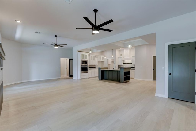 unfurnished living room with light wood-type flooring, ceiling fan, and sink