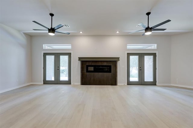 unfurnished living room featuring french doors, a healthy amount of sunlight, and light hardwood / wood-style floors