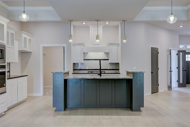 kitchen featuring white cabinetry, light stone countertops, stainless steel appliances, and decorative light fixtures