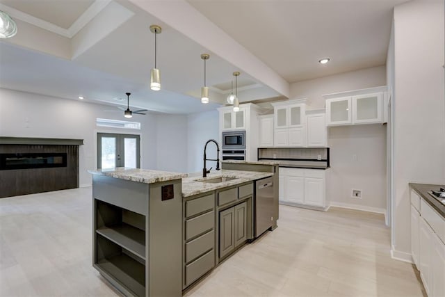 kitchen featuring light stone countertops, stainless steel appliances, sink, a center island with sink, and white cabinets