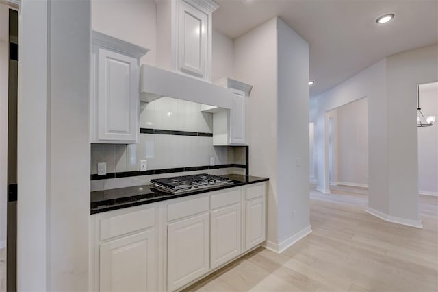 kitchen featuring tasteful backsplash, white cabinetry, light hardwood / wood-style flooring, and stainless steel gas stovetop