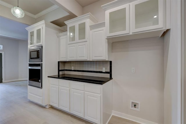 kitchen with appliances with stainless steel finishes, backsplash, crown molding, pendant lighting, and white cabinetry