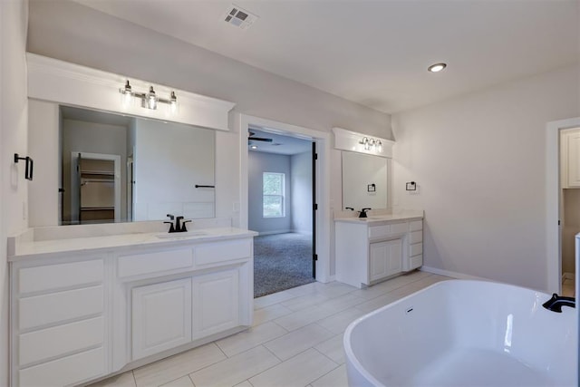 bathroom with a bathing tub, vanity, and tile patterned flooring