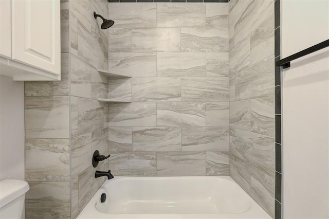 bathroom featuring toilet and tiled shower / bath