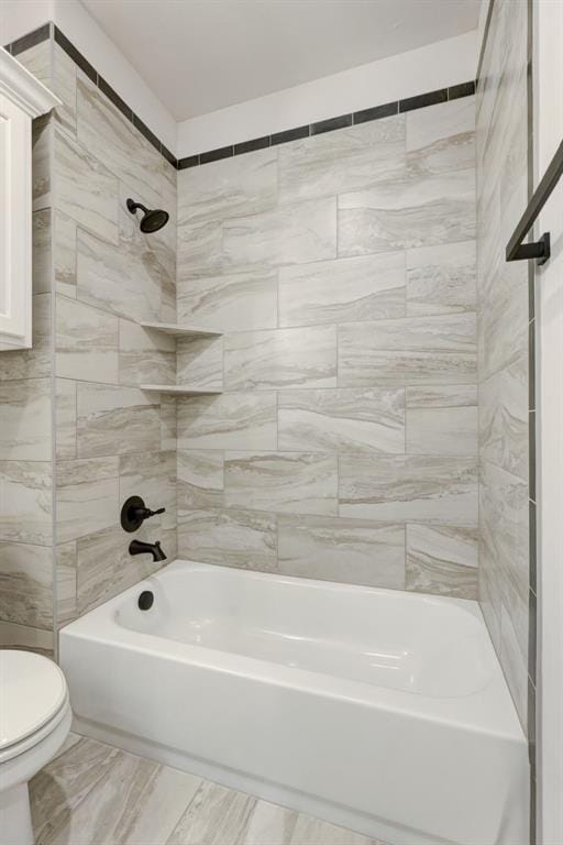 bathroom with tiled shower / bath combo and toilet