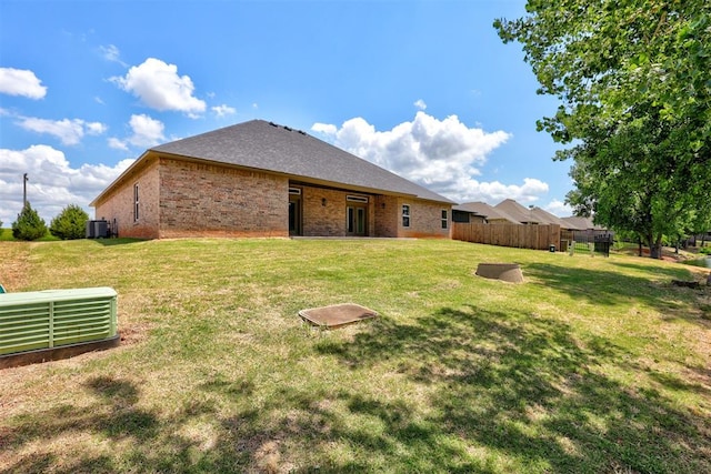 rear view of property with a lawn and central AC