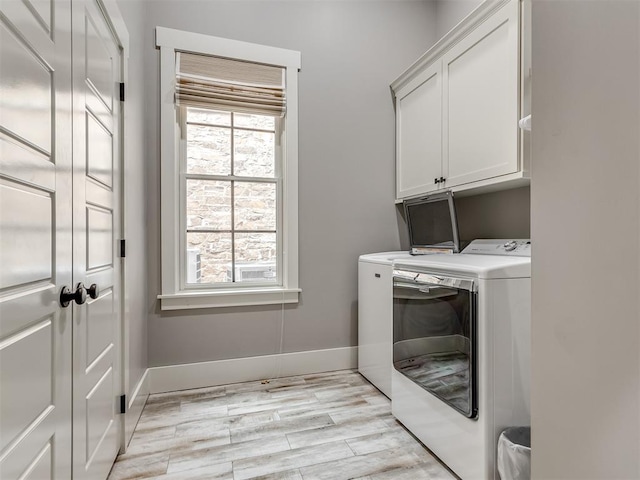 laundry room featuring washer and dryer, light hardwood / wood-style floors, and cabinets