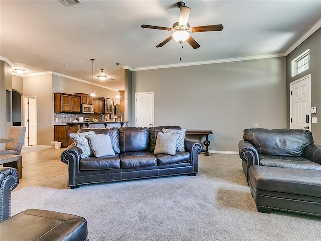 living room featuring ceiling fan, ornamental molding, and light colored carpet