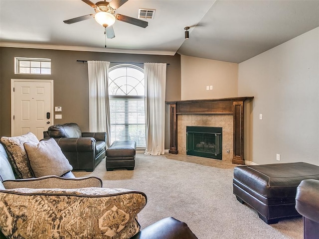 carpeted living room featuring ceiling fan and a tiled fireplace