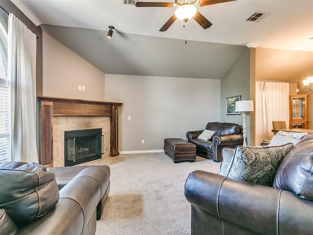 living room with ceiling fan with notable chandelier, a tile fireplace, light carpet, and vaulted ceiling