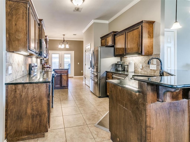 kitchen featuring appliances with stainless steel finishes, decorative backsplash, hanging light fixtures, light tile patterned flooring, and crown molding