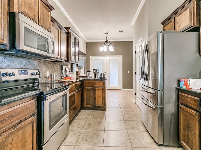 kitchen featuring light tile patterned floors, appliances with stainless steel finishes, decorative light fixtures, a notable chandelier, and crown molding