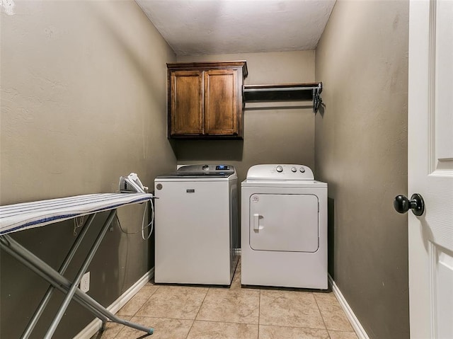 washroom featuring washer and clothes dryer, light tile patterned floors, and cabinets