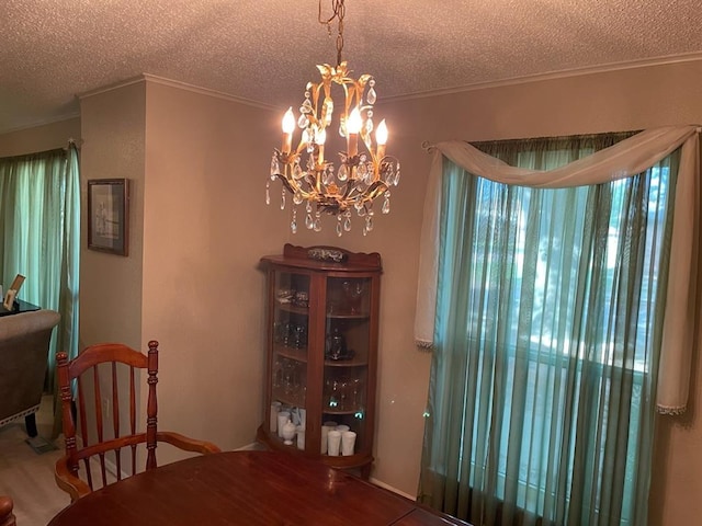 dining area featuring a notable chandelier, ornamental molding, and a textured ceiling