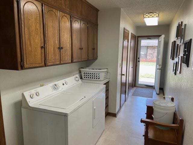 laundry room with cabinets, washer and dryer, and a textured ceiling