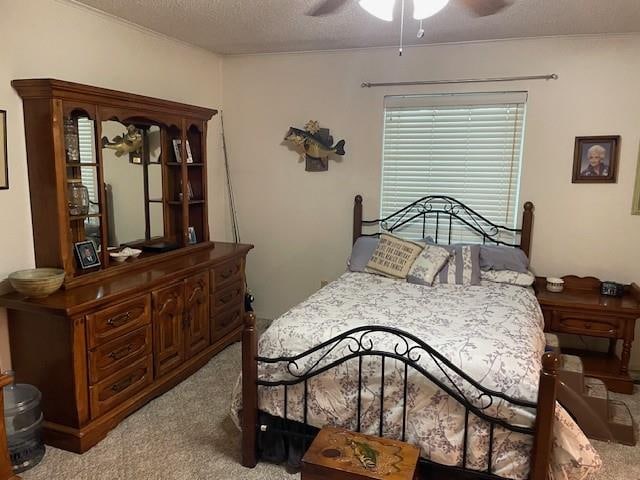 bedroom featuring ceiling fan, light carpet, and a textured ceiling