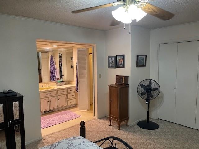 carpeted bedroom featuring ceiling fan, a textured ceiling, and ensuite bath