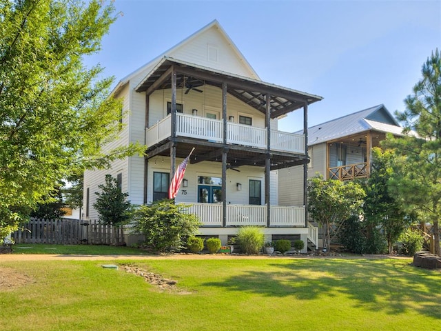 rear view of house featuring ceiling fan, a porch, a balcony, and a yard