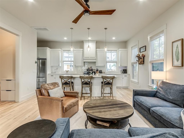 living room featuring light hardwood / wood-style floors, ceiling fan, and a healthy amount of sunlight