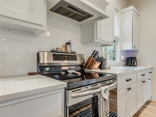 kitchen featuring decorative backsplash, ventilation hood, light hardwood / wood-style flooring, stainless steel range oven, and white cabinets