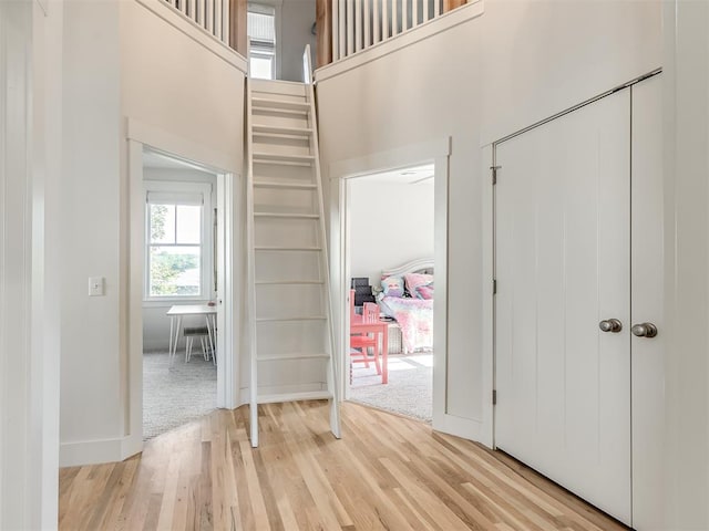 interior space with a towering ceiling and light hardwood / wood-style flooring