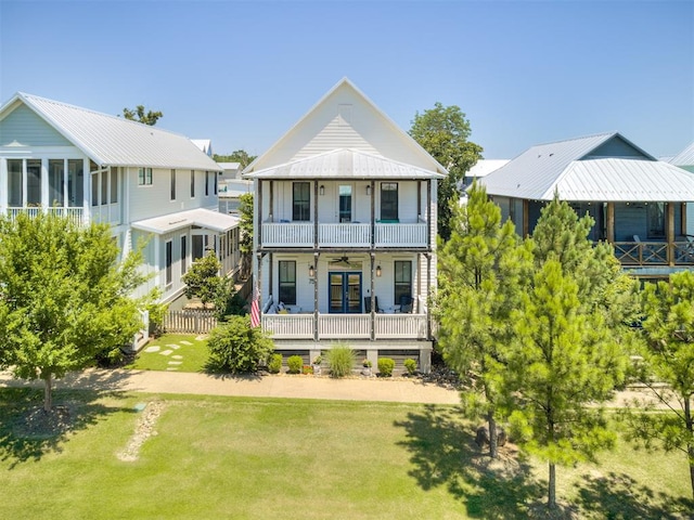 rear view of house with covered porch, a yard, and a balcony