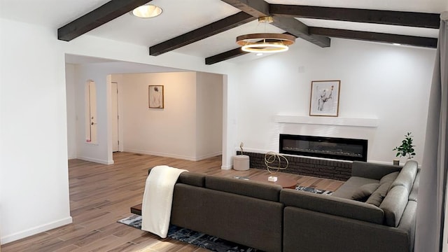 living room with lofted ceiling with beams, light hardwood / wood-style floors, and a fireplace