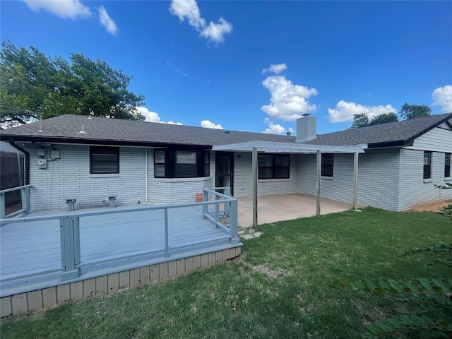 rear view of house featuring a lawn, a wooden deck, and a patio