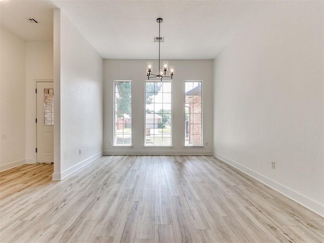 unfurnished dining area featuring a chandelier and light hardwood / wood-style flooring