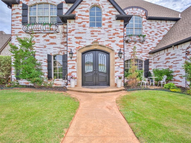 view of exterior entry featuring a lawn and french doors