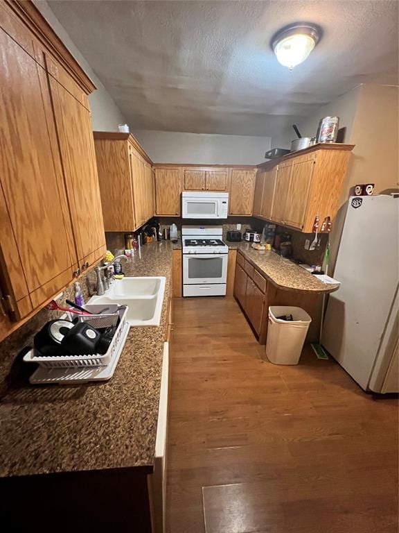 kitchen featuring a textured ceiling, white appliances, dark hardwood / wood-style floors, and sink