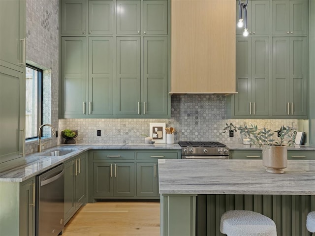 kitchen featuring stainless steel appliances, light stone counters, green cabinets, and sink