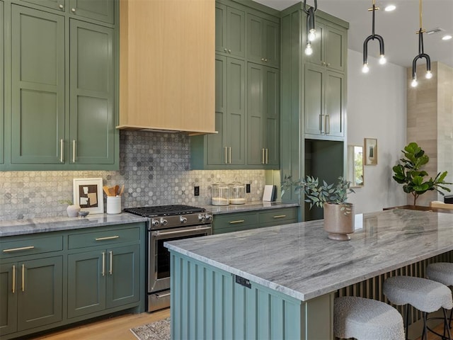 kitchen featuring green cabinetry, light stone counters, hanging light fixtures, and gas range