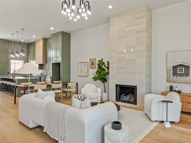 living room with light hardwood / wood-style floors, an inviting chandelier, and a tiled fireplace