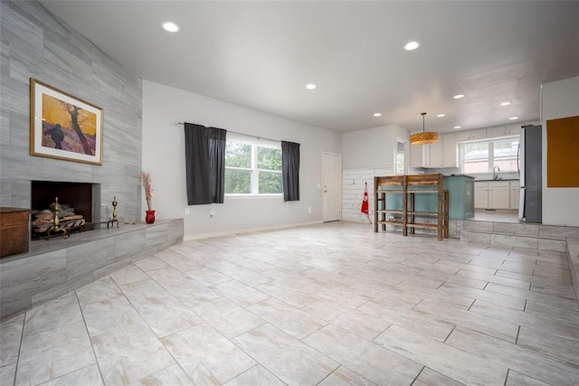 unfurnished living room with sink and a tiled fireplace