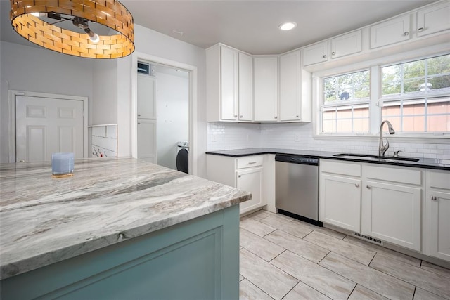 kitchen with white cabinets, washer / clothes dryer, stainless steel dishwasher, and dark stone counters