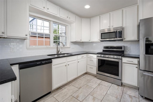 kitchen with stainless steel appliances, white cabinetry, tasteful backsplash, and sink