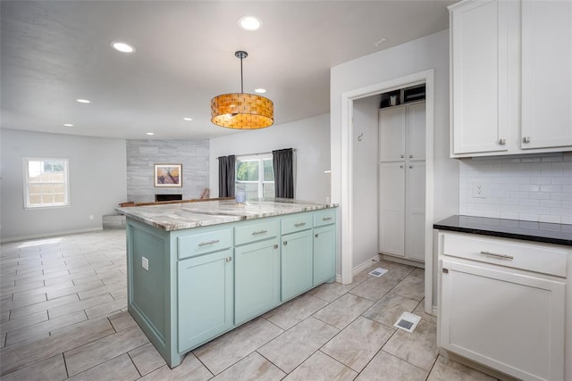 kitchen with decorative backsplash, plenty of natural light, white cabinets, and hanging light fixtures