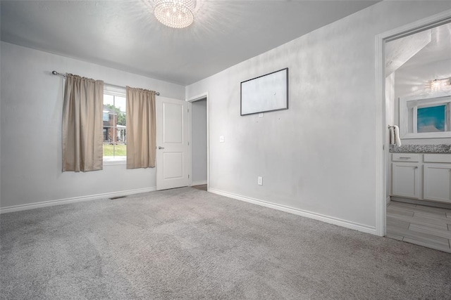 carpeted empty room with an inviting chandelier