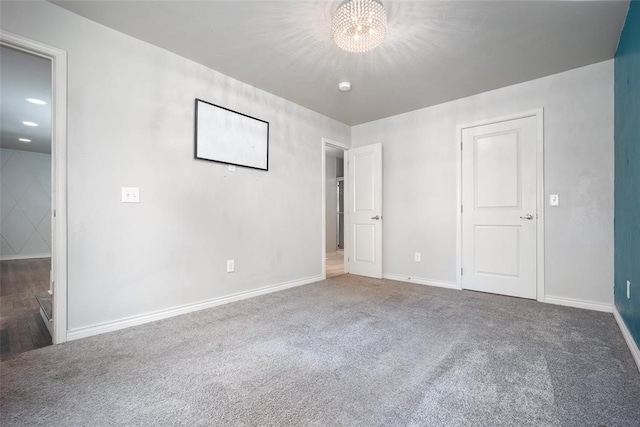 unfurnished bedroom with a notable chandelier and dark carpet