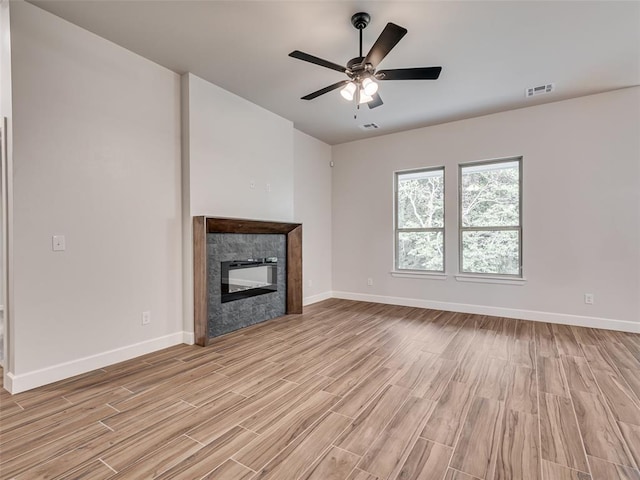 unfurnished living room with ceiling fan, light hardwood / wood-style floors, and a premium fireplace