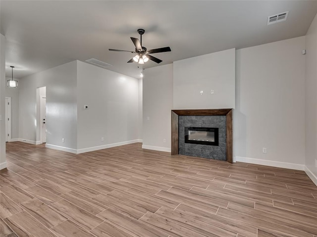 unfurnished living room featuring ceiling fan, light wood-type flooring, and a fireplace