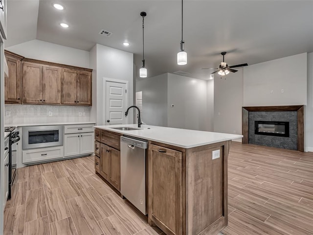 kitchen featuring stainless steel dishwasher, black range oven, ceiling fan, sink, and a stone fireplace